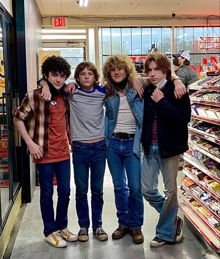 four young men are posing for a photo in a grocery store with their arms around each other