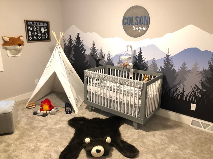 a baby's room with a teepee tent and mountain mural