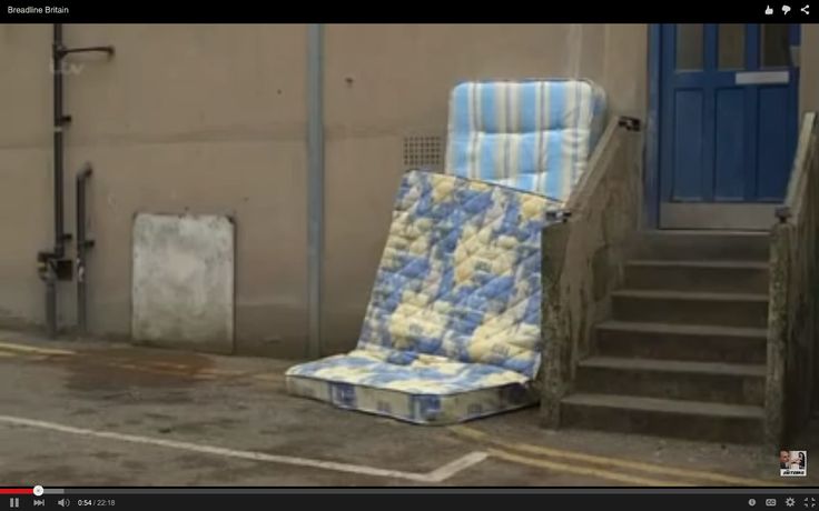 a blue and white chair sitting on the side of a building next to stairs with an open door