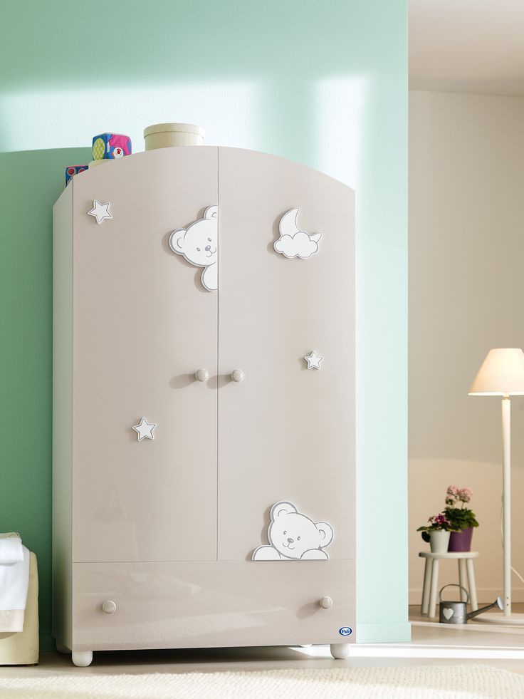 a child's room with a white cabinet and green walls, including a teddy bear decal on the door