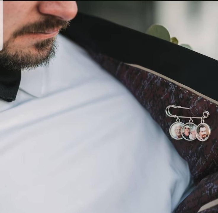 a man in a white shirt and bow tie with two earrings on his lapel