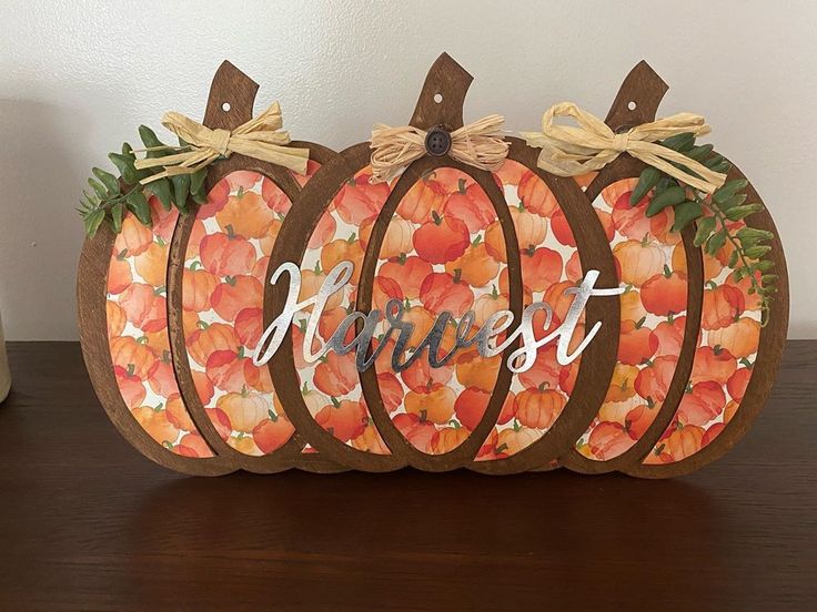 a painted pumpkin sitting on top of a wooden table with the word harvest written on it