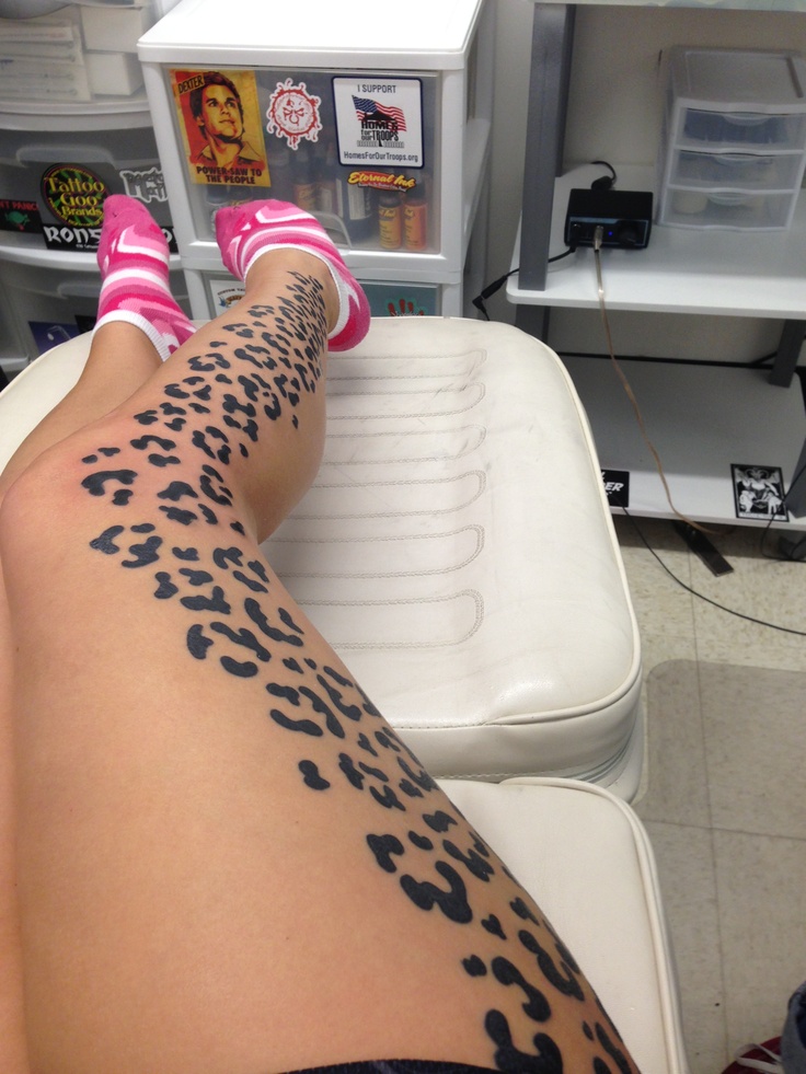 a person with tattoos on their legs sitting in a chair