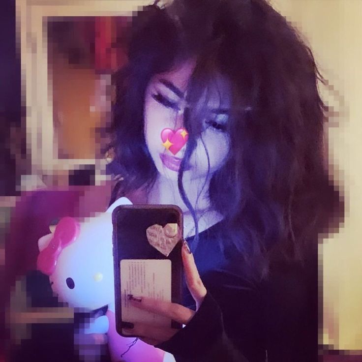 a woman holding a cell phone with a heart on it's nose and looking at the screen