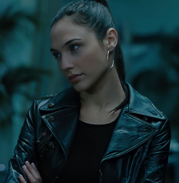 a woman wearing a black leather jacket and earrings