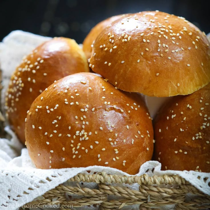 four buns with sesame seeds in a basket