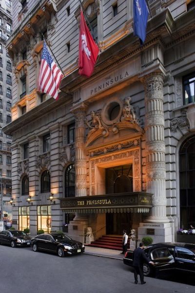 the peninsula hotel in new york city is lit up at night with american flags flying