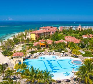 an aerial view of the resort and pool area with palm trees, blue water and white sand