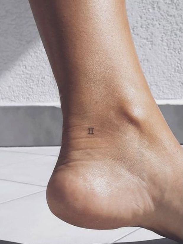 a person's foot with the word pi tattooed on it, in front of a white wall