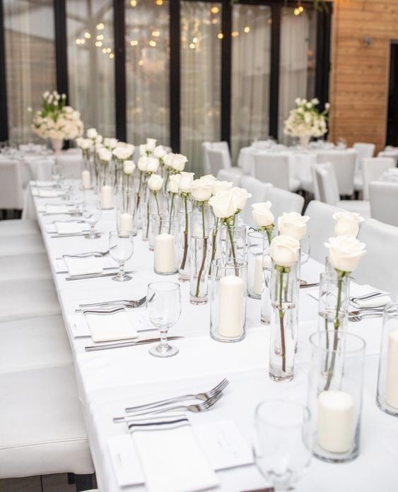 a long table is set with white flowers and candles