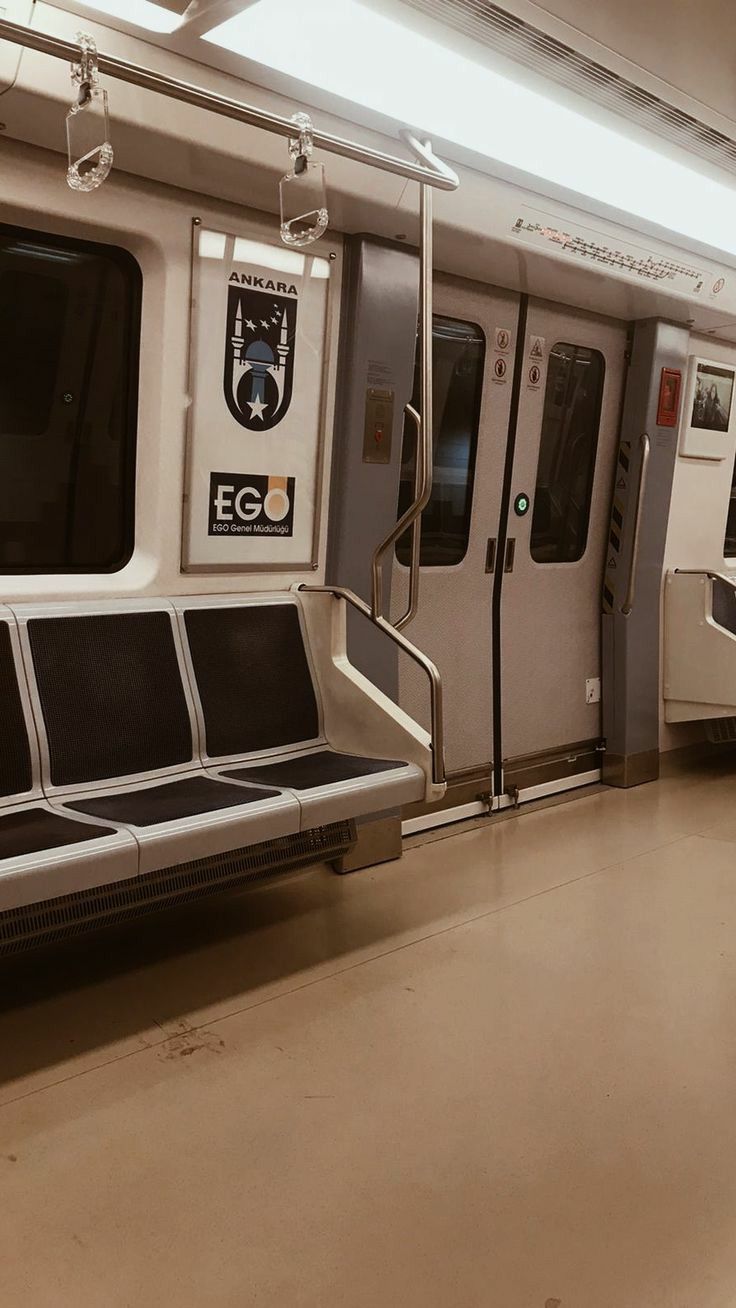 the inside of a subway train with seats and railings on both sides, facing forward