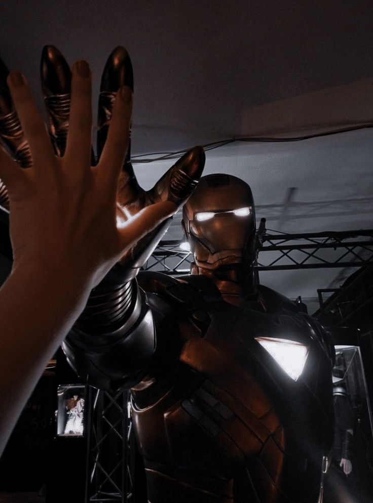 an iron man statue being held up by someone's hand in front of him