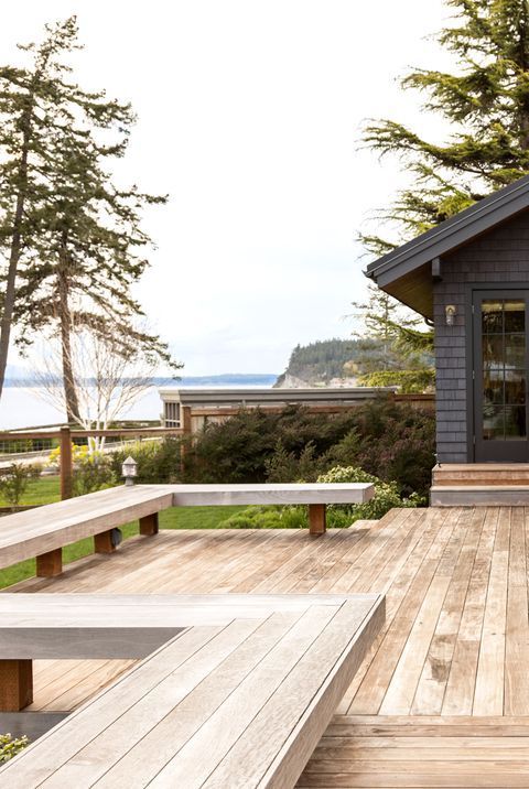 a wooden deck with benches next to a house