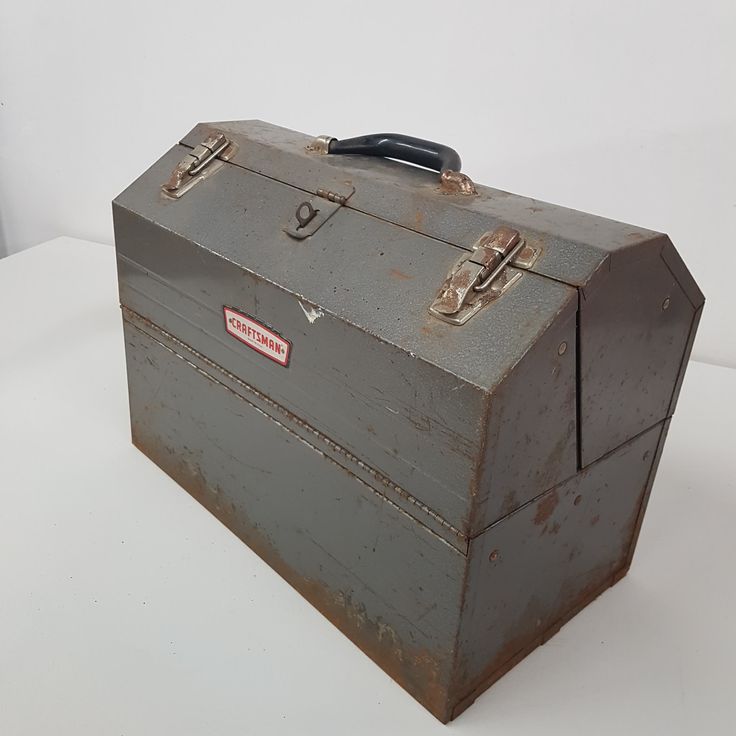 an old metal box sitting on top of a white table next to a black handle