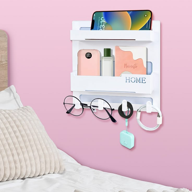 an eyeglass holder is hanging on the wall next to a bed with pink walls