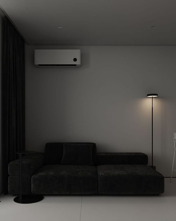 a black and white living room with an air conditioner on the wall next to a couch