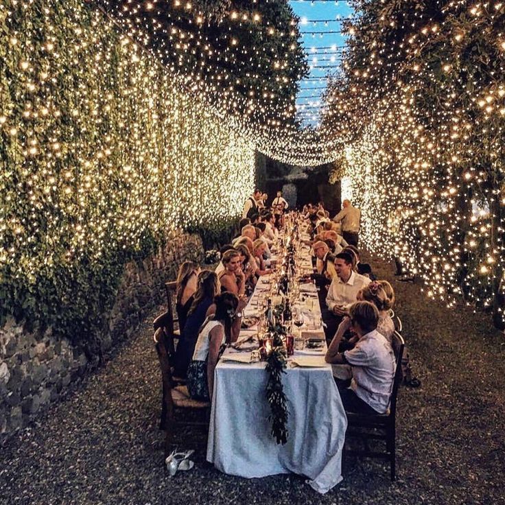 a group of people sitting at a long table in the middle of a tunnel filled with lights