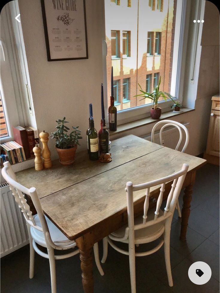 a table with chairs and bottles of wine on it in front of a large window