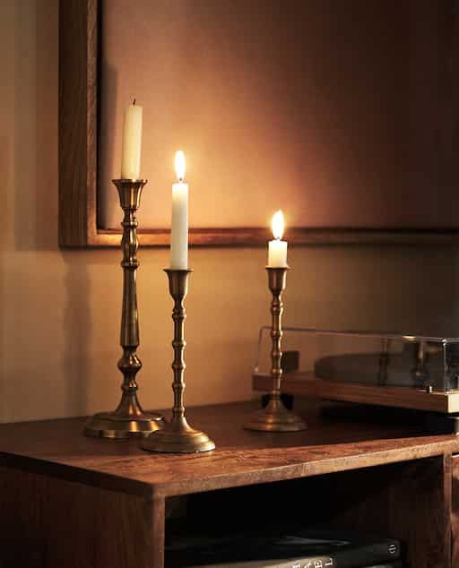 three candles are lit on a wooden table in front of a mirror and record player