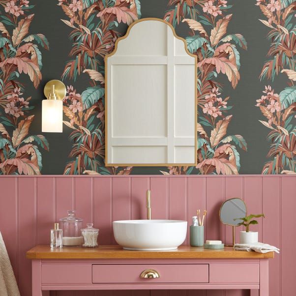 a bathroom with pink and green wallpaper, a sink and mirror in the corner