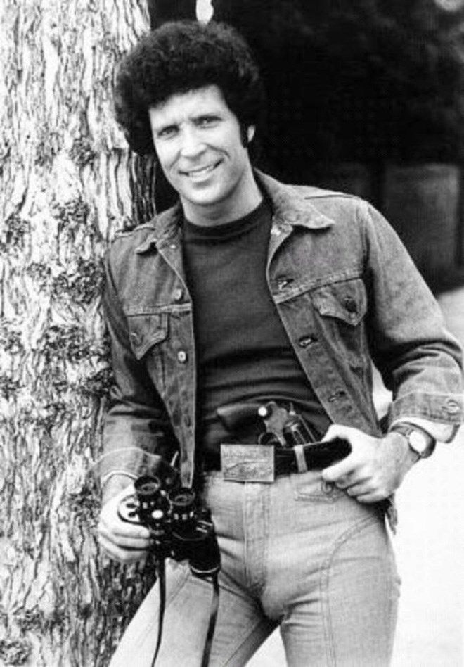 a man standing next to a tree holding a camera