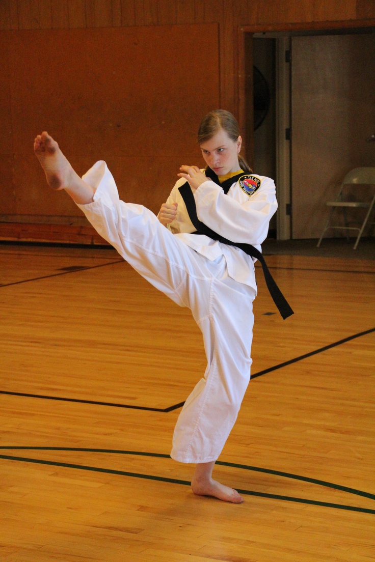 a woman is practicing karate in an indoor gym with hard wood flooring and walls