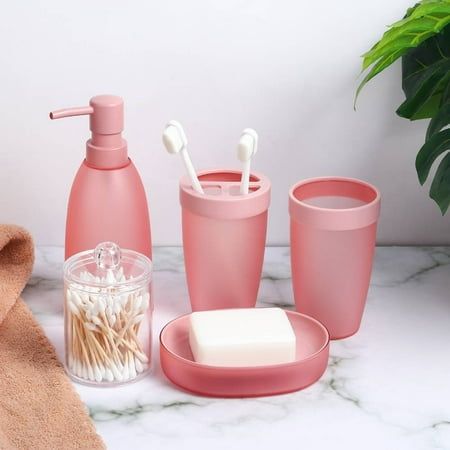 pink bathroom accessories including soap, toothbrushes and other items on a marble countertop