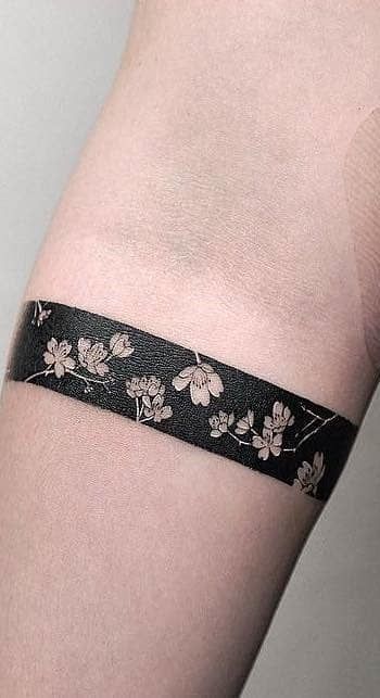 a woman's arm with a black and white flowered wristband on it