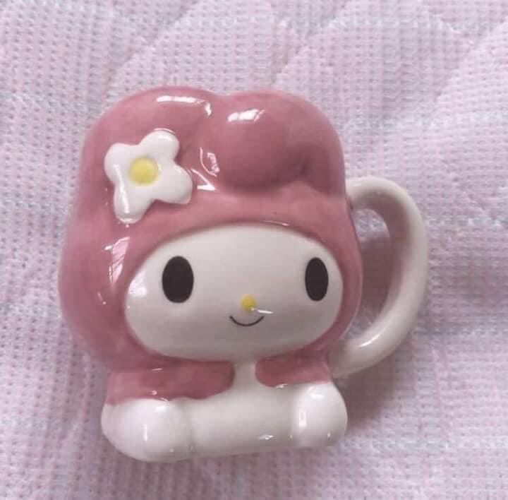 a pink and white hello kitty coffee cup with a flower in it's hair