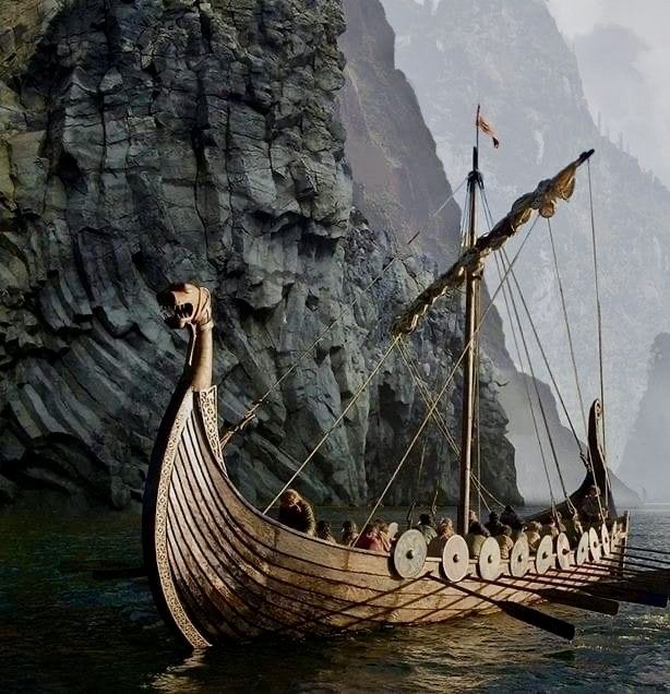 an old boat with many people on it in the water next to a rocky cliff