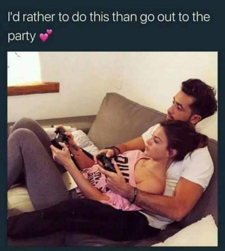 a man and woman sitting on top of a couch holding video game remotes in their hands