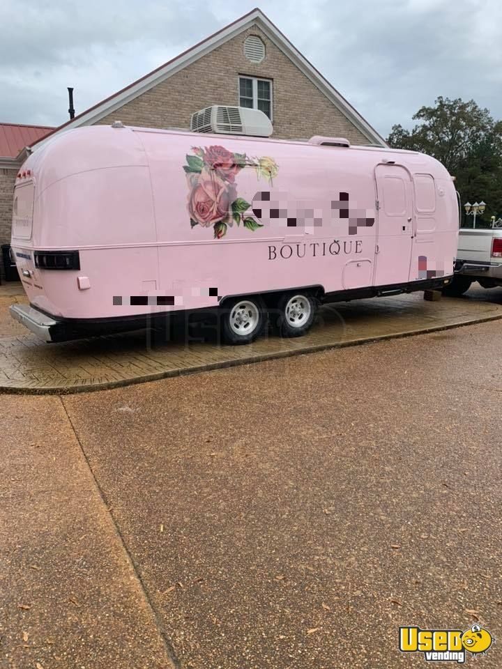 a pink trailer is parked in front of a house with flowers painted on the side