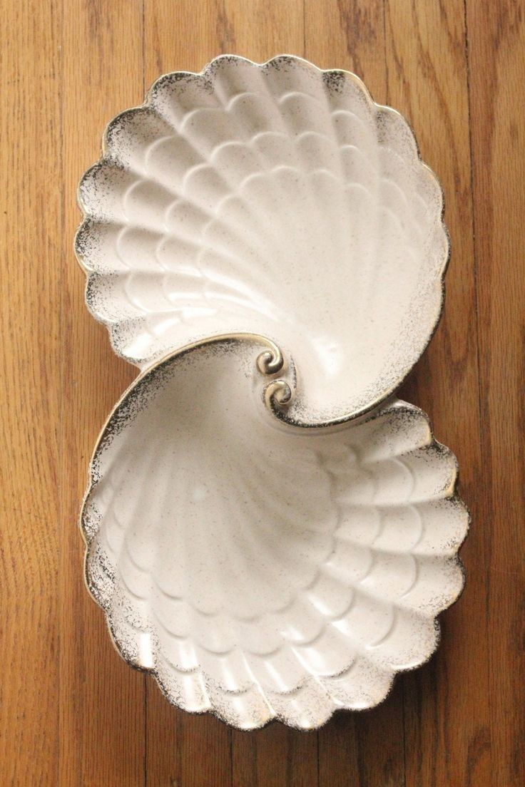 two white dishes sitting on top of a wooden table next to each other and one is holding an object in the middle