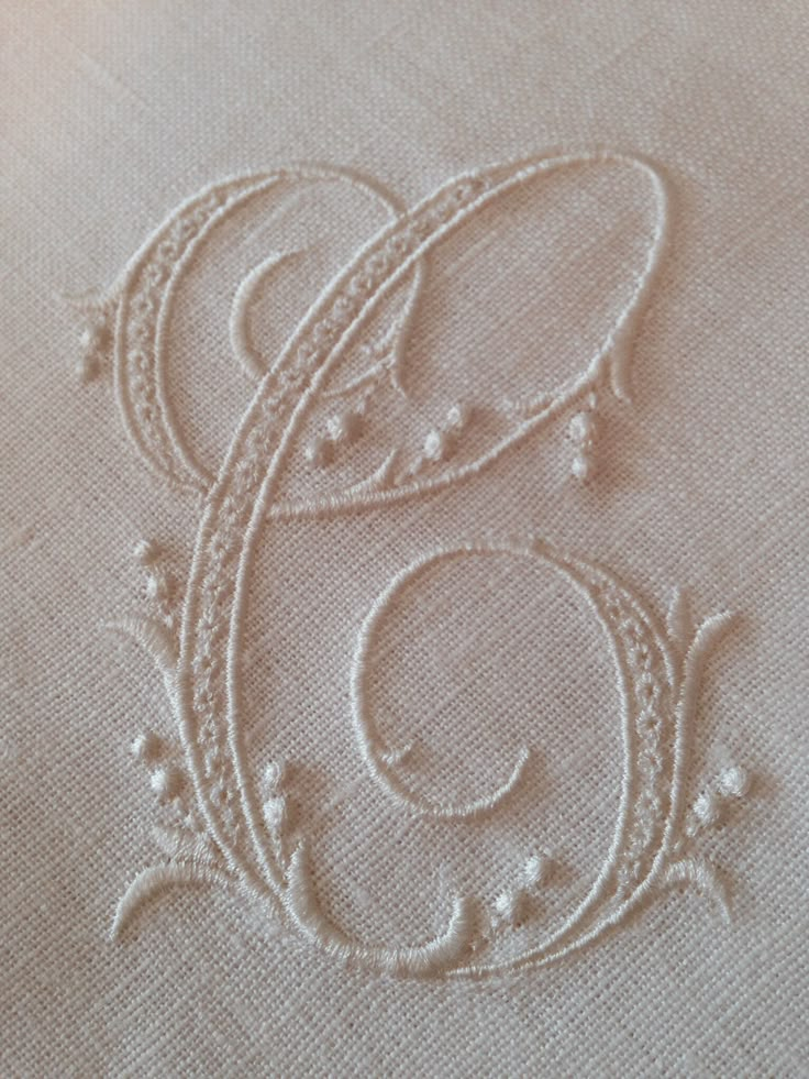 an embroidered monogrammed letter e on a linen pillow