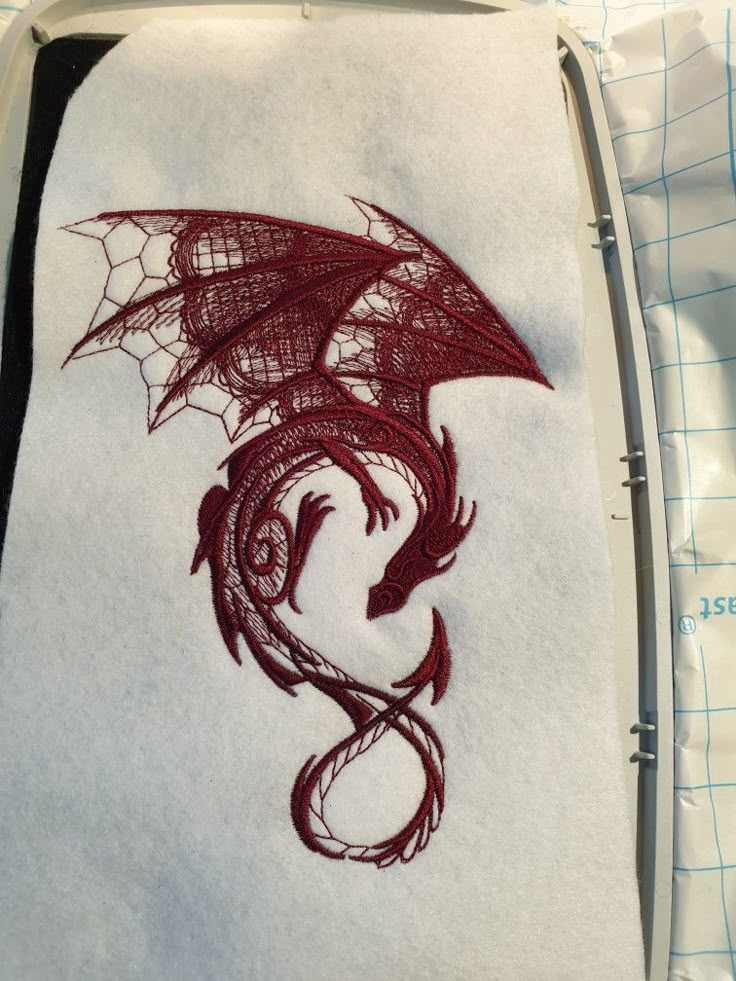 a red dragon embroidered onto a white piece of cloth