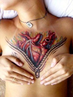 a woman's chest with a heart tattoo on it and two hands holding her chest