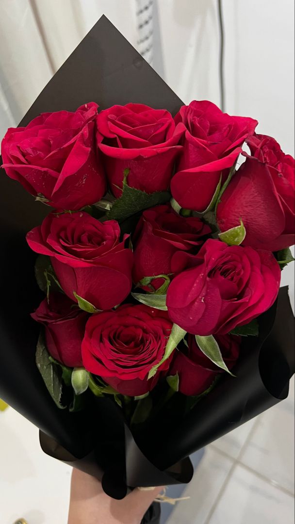 a person holding a bouquet of red roses