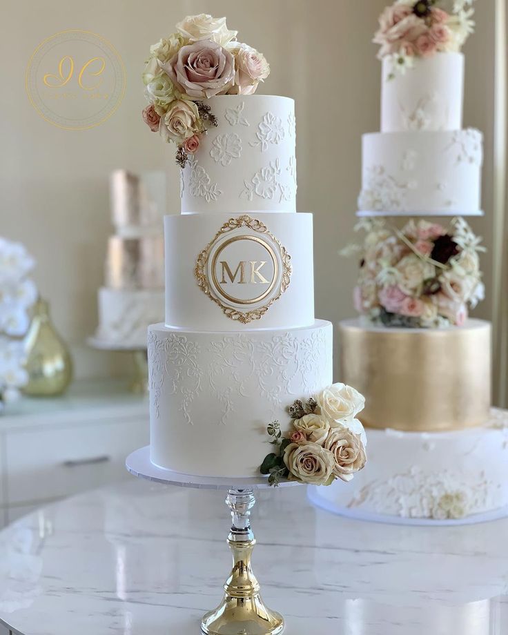 a three tiered wedding cake with white flowers on the top and gold trimmings