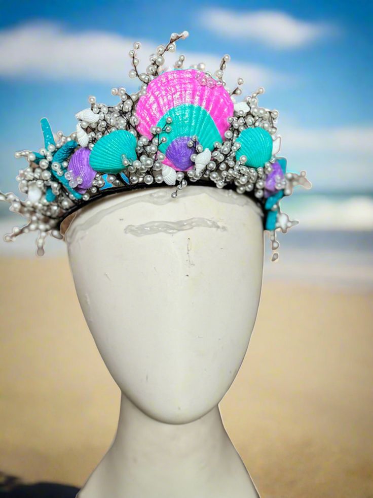 Pearls and Shells Mermaid Crown Dive into the enchanting world of mermaids with our Hand Made, Hand-painted Pearls and Shells Mermaid Crown by The Head Mistress. Transform into a majestic sea princess with this exquisite crown adorned with hand-painted shells and shimmering glitter finish. Key Features: Perfect for Mermaid Photoshoots: Capture stunning mermaid moments with this crown. Adjustable Metal Base: Ensures a comfortable fit and comes with loops for secure fastening using bobby pins. Designed for Ages 6 and Up: Ideal for young mermaid princesses ready to make a splash. Indulge in the magic of the sea and elevate your mermaid look with our Pearls and Shells Mermaid Crown. Purchase two crowns and enjoy free shipping to complete your transformation into a finned diva of the sea! Mermaid Look, Sea Princess, Mermaid Crown, Fabric Photography, Painted Shells, Mermaid Princess, Photography Backdrops, Metal Base, The Head