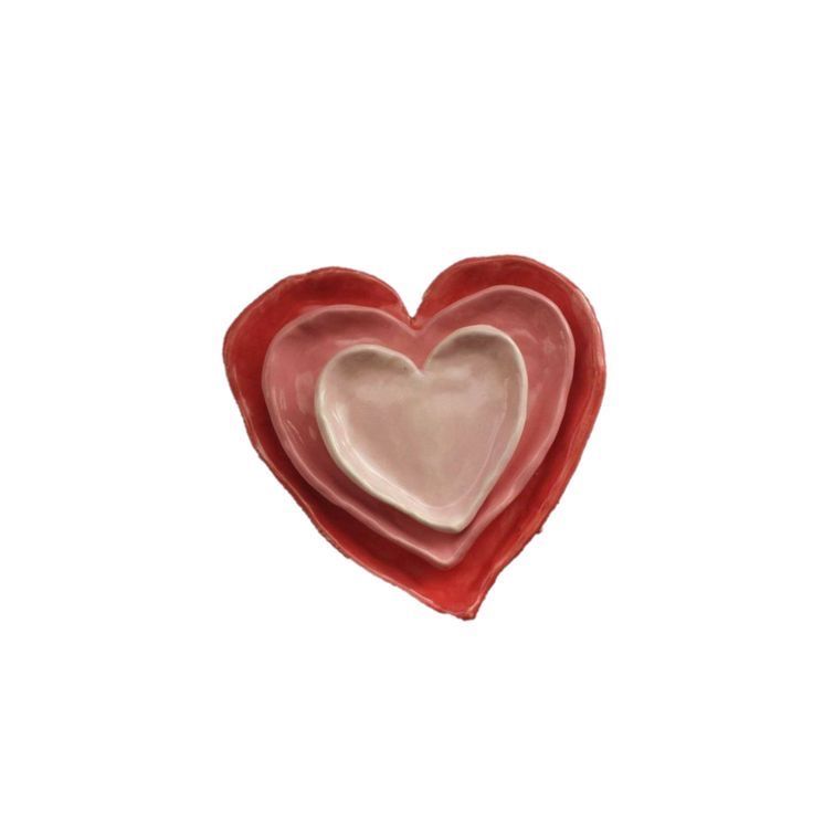 a red heart shaped dish sitting on top of a white table