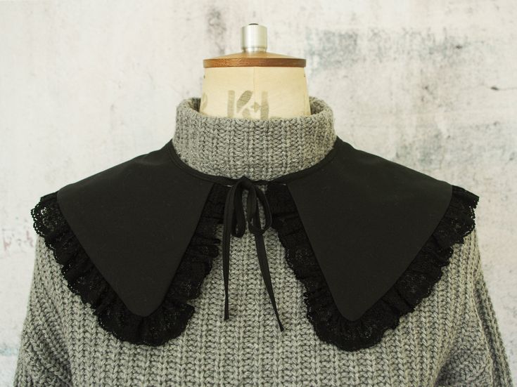 a gray and black jacket with ruffles on the collar