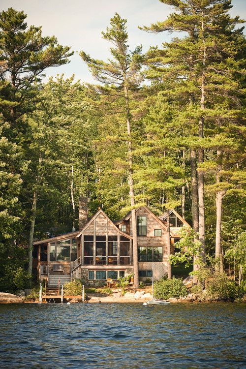 a large house sitting on top of a lake surrounded by trees