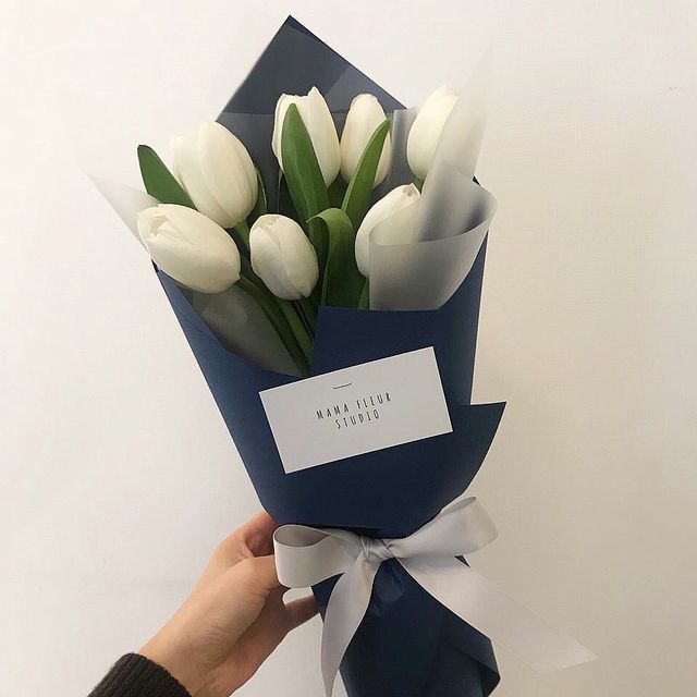 a person holding a bouquet of white tulips with a name tag on it