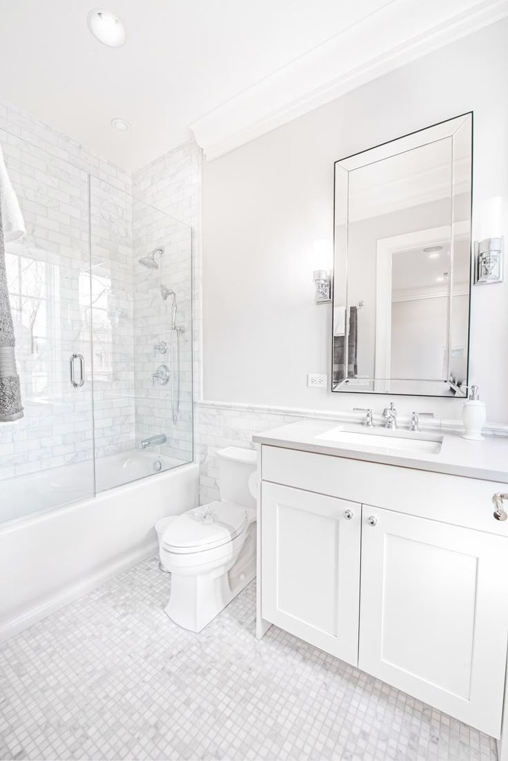 a white bathroom with two sinks, a toilet and a bathtub in it's corner