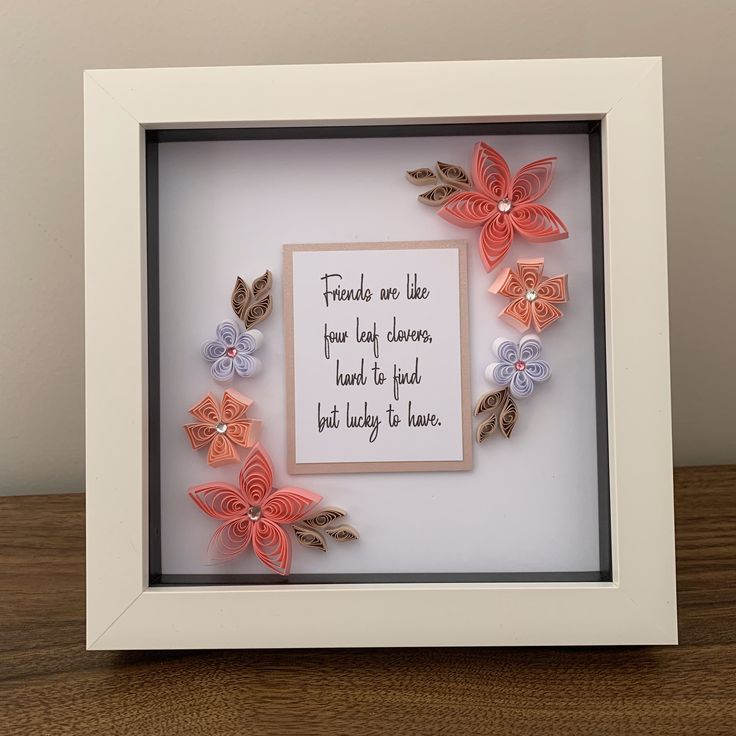 a frame with some paper flowers and a quote in it that says friends are like four leaf shapes