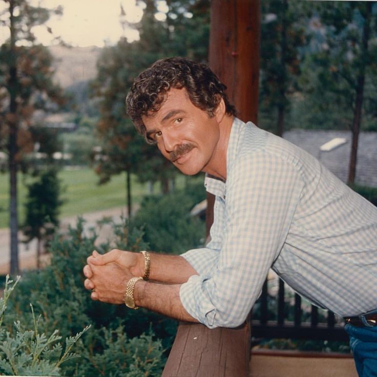 a man leaning on a rail with his hands in the air and looking at the camera