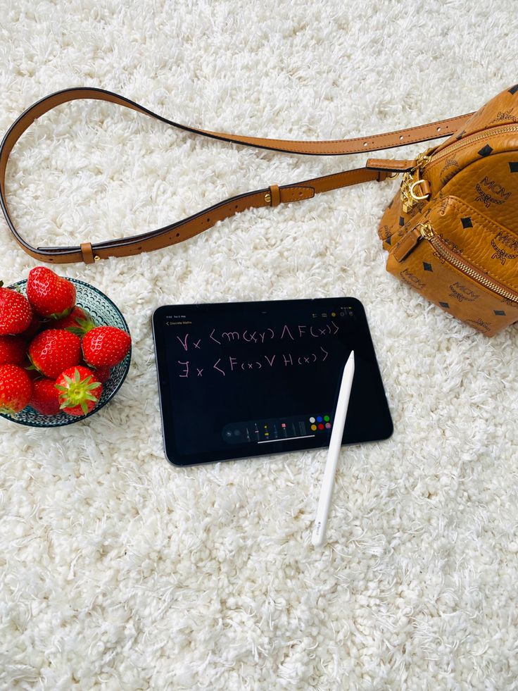 strawberries are sitting on the floor next to a purse and a notepad with writing