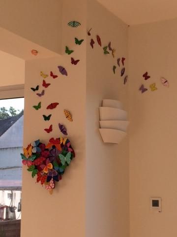 there are many colorful butterflies on the wall in this room, and one is hanging from the ceiling