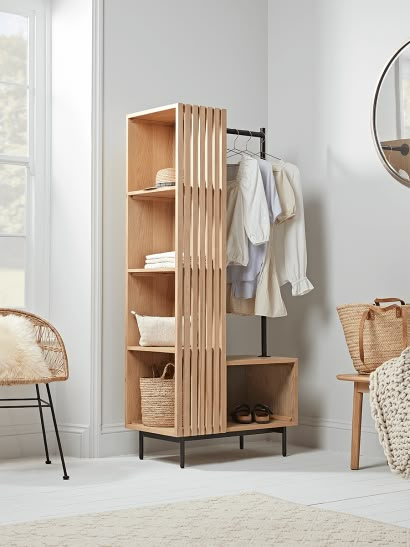 an open closet with clothes hanging on it and a chair in the corner next to it