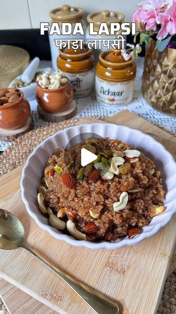 a bowl filled with food sitting on top of a wooden cutting board next to jars and spoons